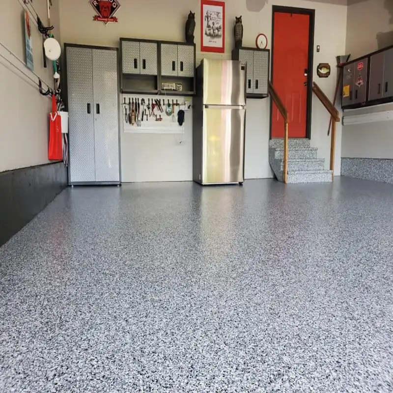 Gray speckled epoxy floor in a garage with red door