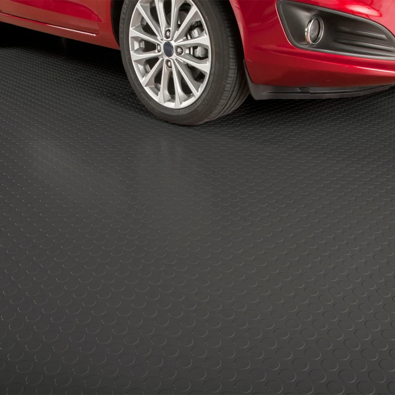 Red car parked on black coin-pattern rubber flooring