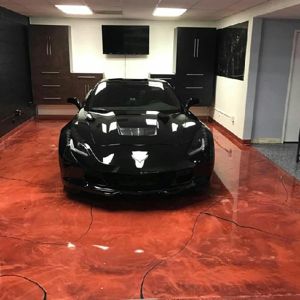 Black Corvette on a red metallic epoxy garage floor with a cracked effect.