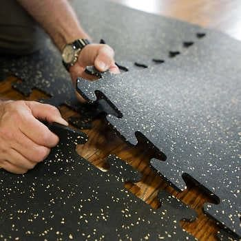 Hands connecting interlocking rubber gym floor tiles