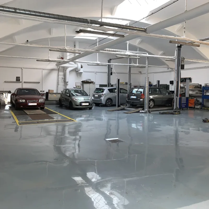 Modern garage with epoxy flooring, car lifts, and vehicles