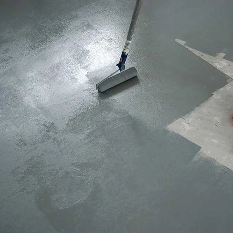 Applying gray epoxy paint to a concrete floor with a roller.