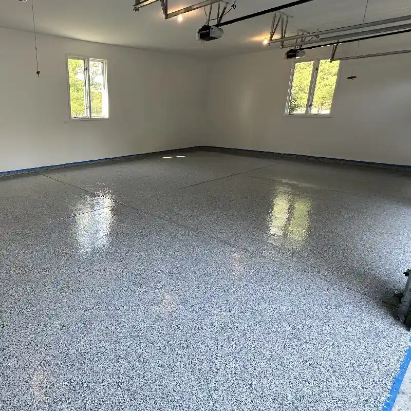 Newly painted garage floor with gray epoxy coating and blue painter's tape