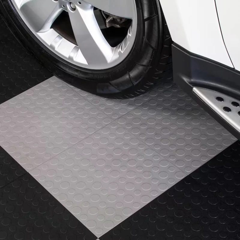 Garage Flooring Tiles 71 Gray coin-top garage flooring tiles under a car wheel and running board.